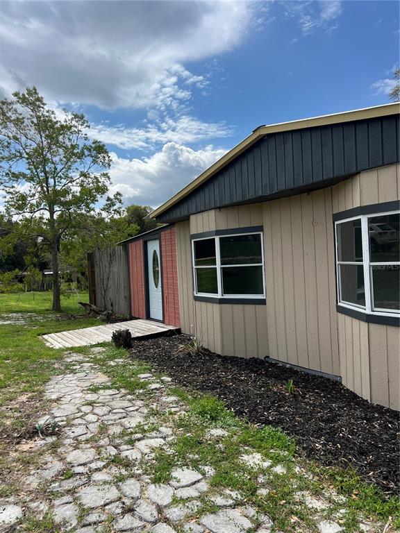 The exterior of a tan house features a dark roof, a white door, and windows — 6287 MAGNOLIA STREET, KEYSTONE HEIGHTS, FL