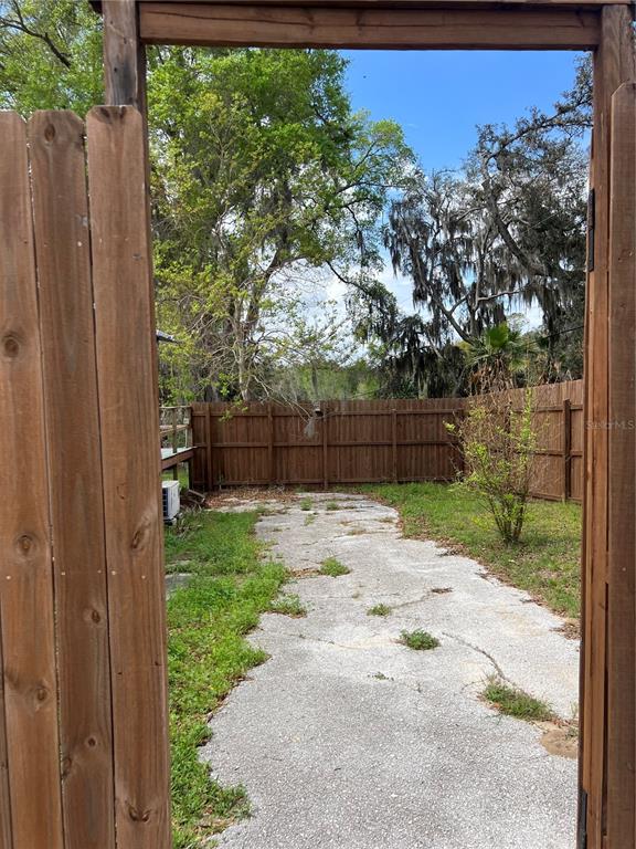 A wooden gate opens to a cracked concrete patio enclosed by a wooden privacy fence — 6287 MAGNOLIA STREET, KEYSTONE HEIGHTS, FL