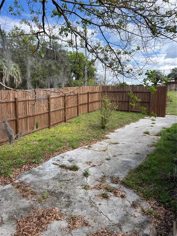 A cracked concrete driveway leads to a wooden privacy fence in a grassy backyard — 6287 MAGNOLIA STREET, KEYSTONE HEIGHTS, FL