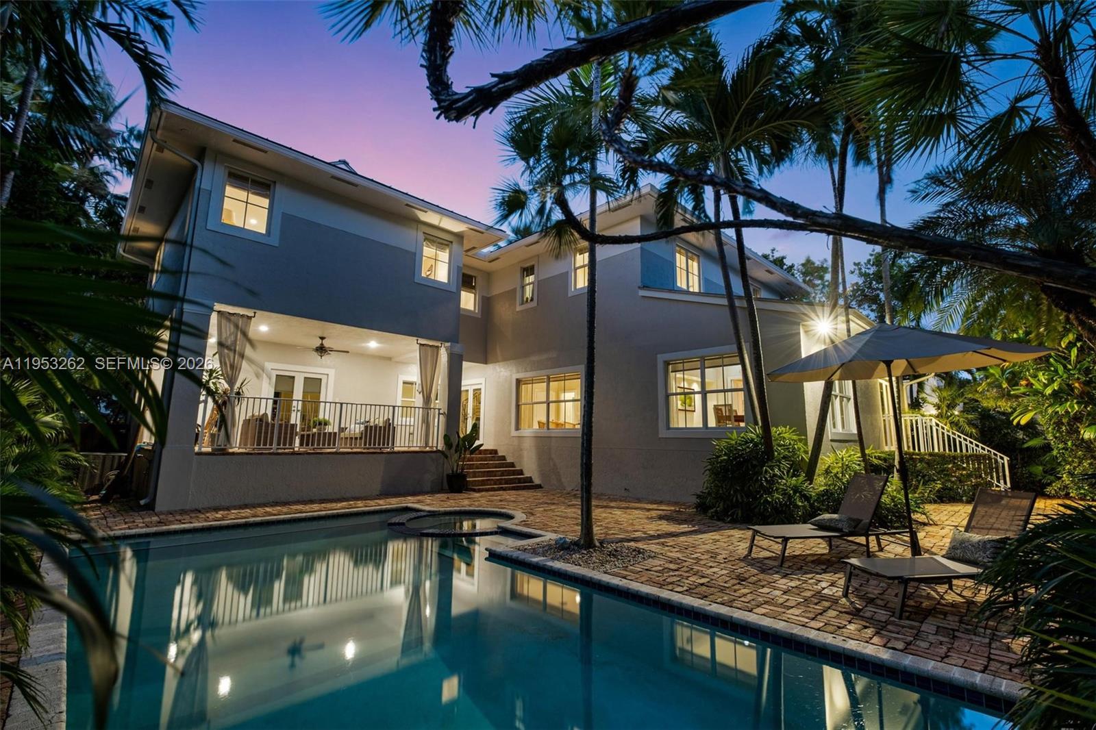 A two-story house with a pool, patio, and palm trees at dusk — 164 W Mashta Dr, Key Biscayne FL 33149, KEY BISCAYNE, FL