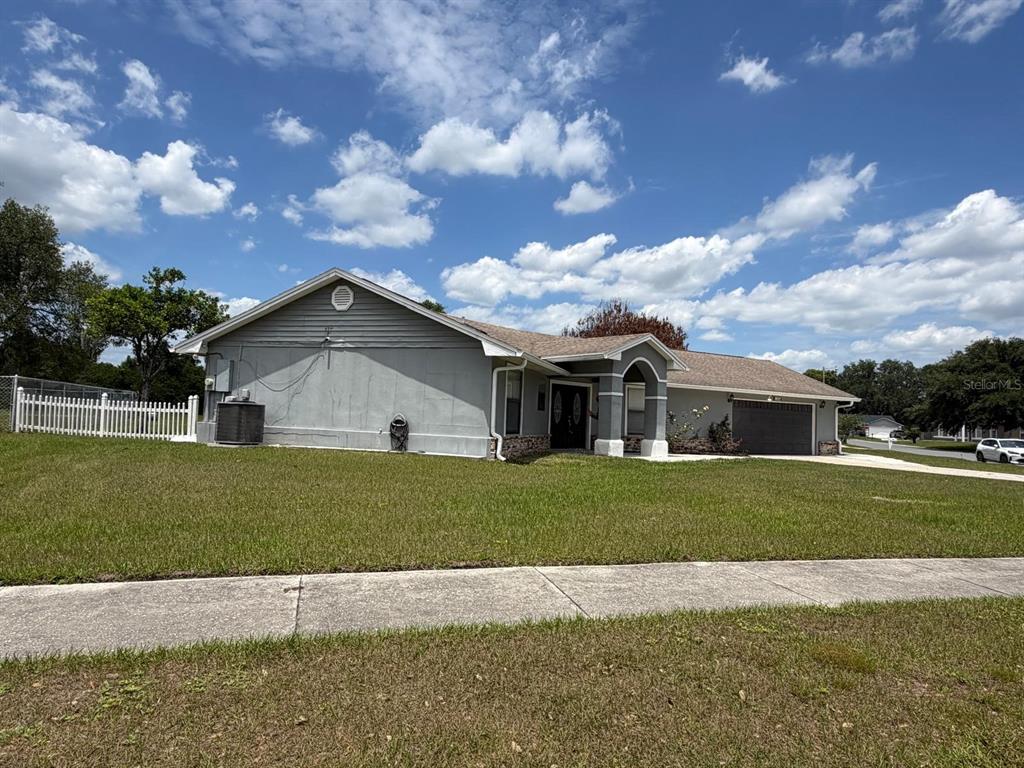 A single-story house with a gray exterior, a front-facing garage, and a white picket fence — 2356 ROYALE OAKS BOULEVARD, KISSIMMEE, FL