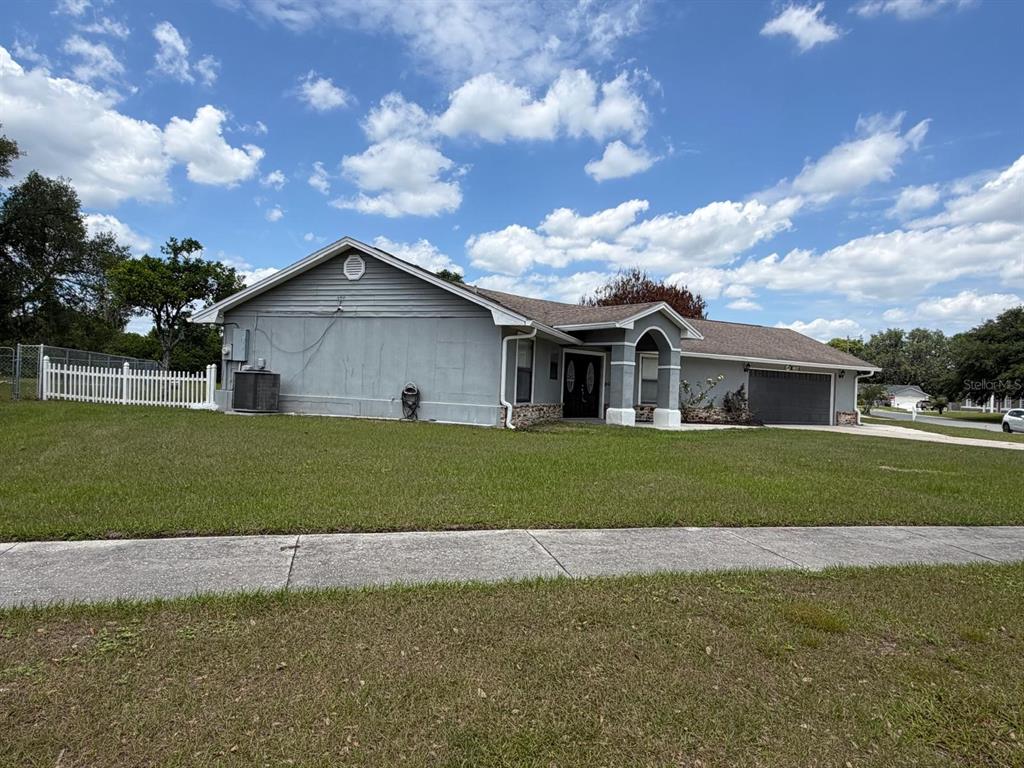 A gray single-story house with a garage and a white picket fence on a lawn — 2356 ROYALE OAKS BOULEVARD, KISSIMMEE, FL