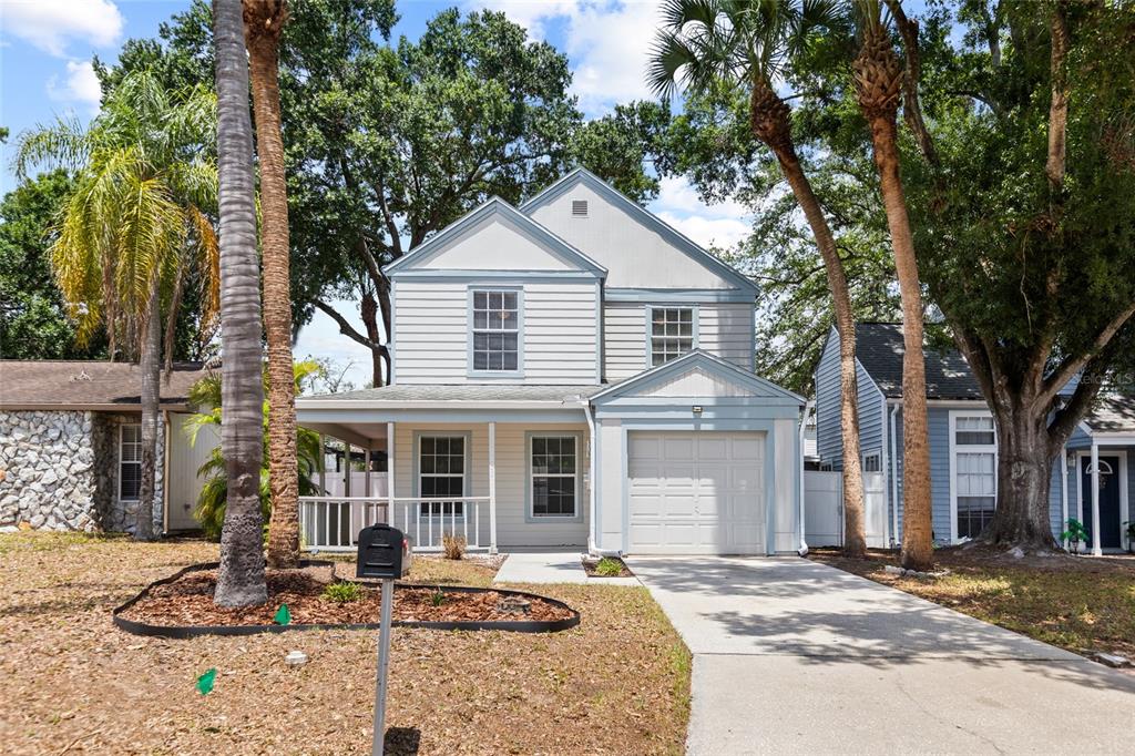 A two-story house with light siding, a front porch, and an attached one-car garage — 7608 WILLOW PARK DRIVE, TEMPLE TERRACE, FL