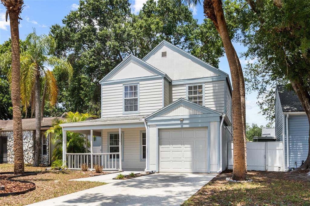 A living room features tile floors, a patterned area rug, two windows, and a front door — 7608 WILLOW PARK DRIVE, TEMPLE TERRACE, FL