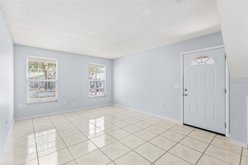 A living room features a beige sofa, two blue armchairs, and a patterned area rug — 7608 WILLOW PARK DRIVE, TEMPLE TERRACE, FL
