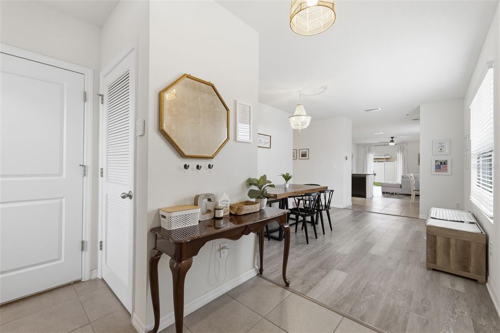 A bright entryway features a console table, an octagonal mirror, and a view into the dining area — 16163 SILENT SANDS LANE, ODESSA, FL