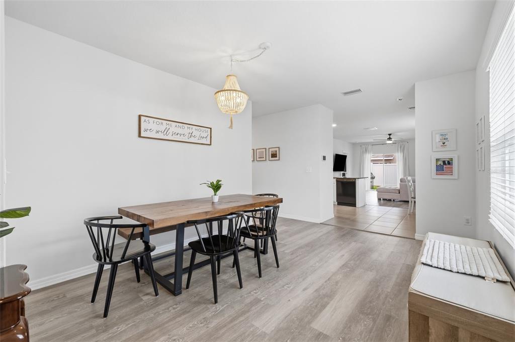 A dining area with a wooden table, black spindle chairs, and a beaded chandelier — 16163 SILENT SANDS LANE, ODESSA, FL