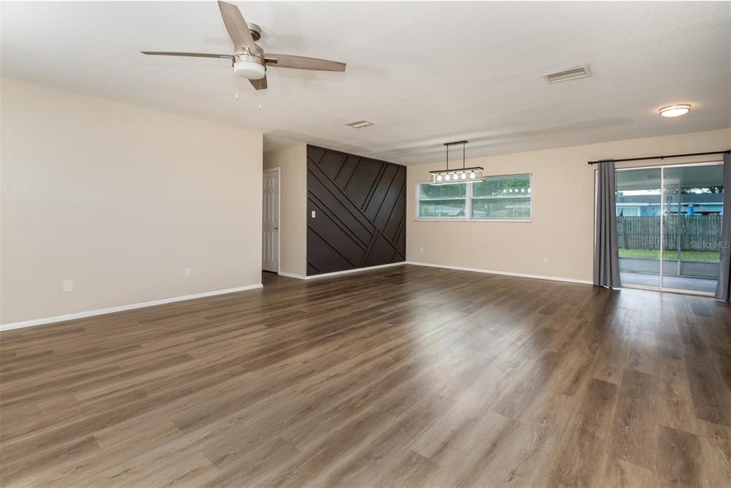 A spacious living and dining area featuring wood-look flooring and a dark geometric accent wall — 1531 VALENCIA STREET, CLEARWATER, FL