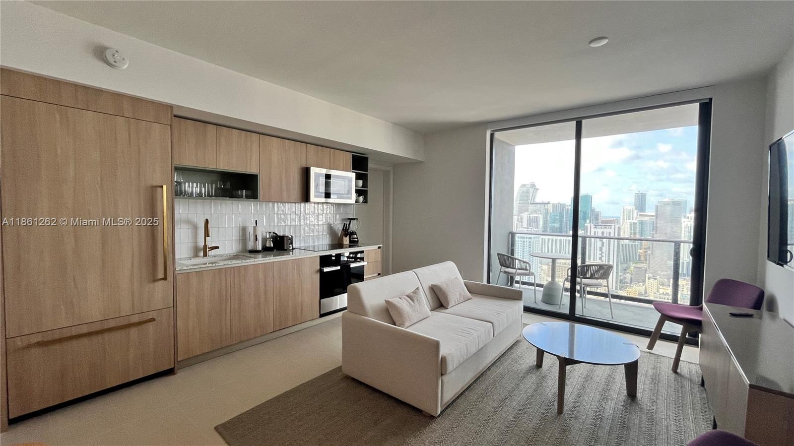 A modern studio apartment features a kitchenette, a sofa, and a balcony with city views — 159 NE 6th St # 4605, Miami FL 33132, MIAMI, FL