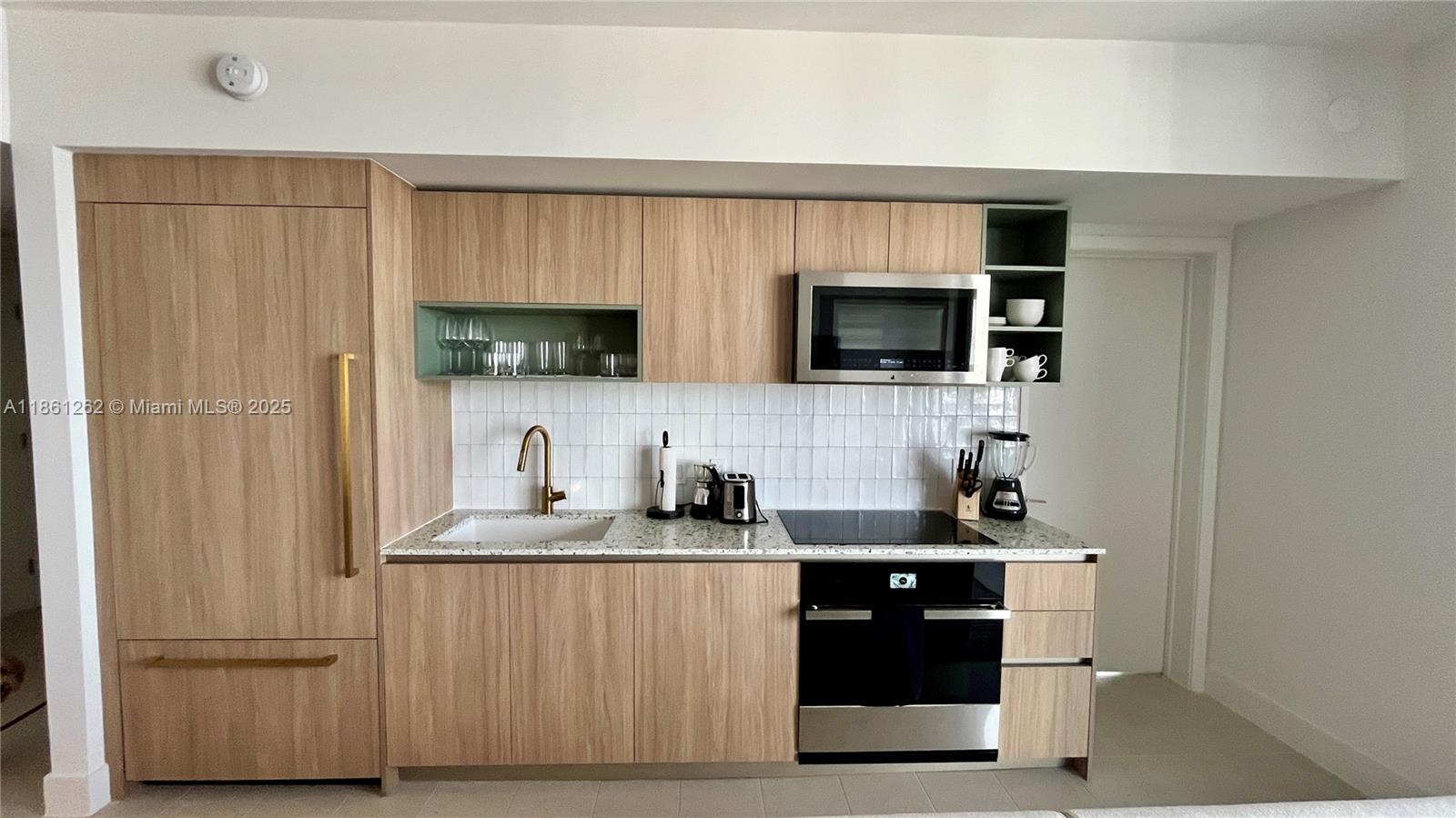 A modern kitchen features light wood cabinetry, white tile backsplash, and stainless steel appliances — 159 NE 6th St # 4605, Miami FL 33132, MIAMI, FL