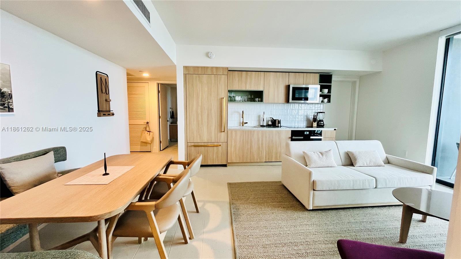 An open-concept living area features a light wood kitchen, dining table, and a white sofa — 159 NE 6th St # 4605, Miami FL 33132, MIAMI, FL