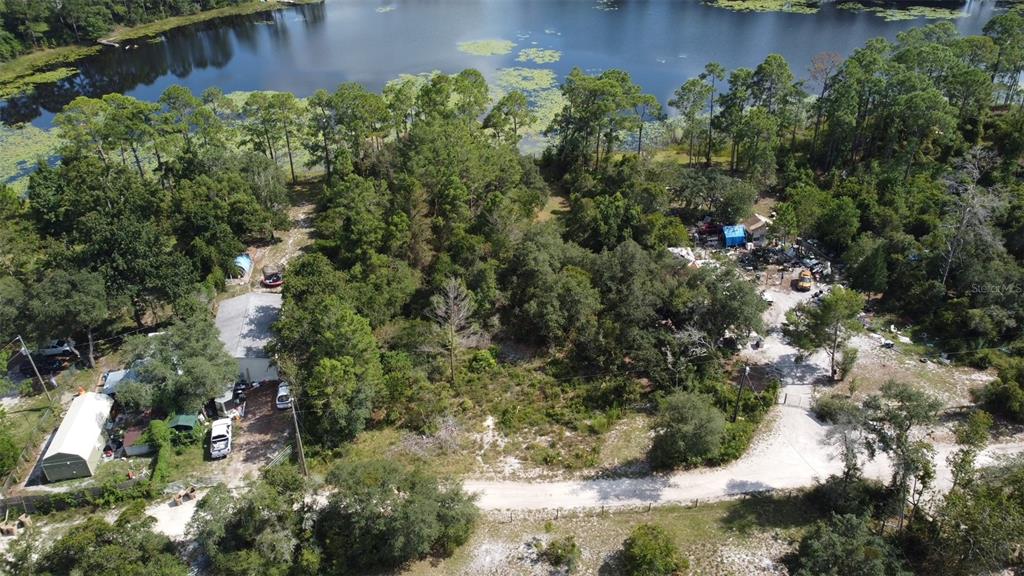An aerial view shows a wooded lot with two structures near a lake and road — W LAKE ROAD, DELAND, FL