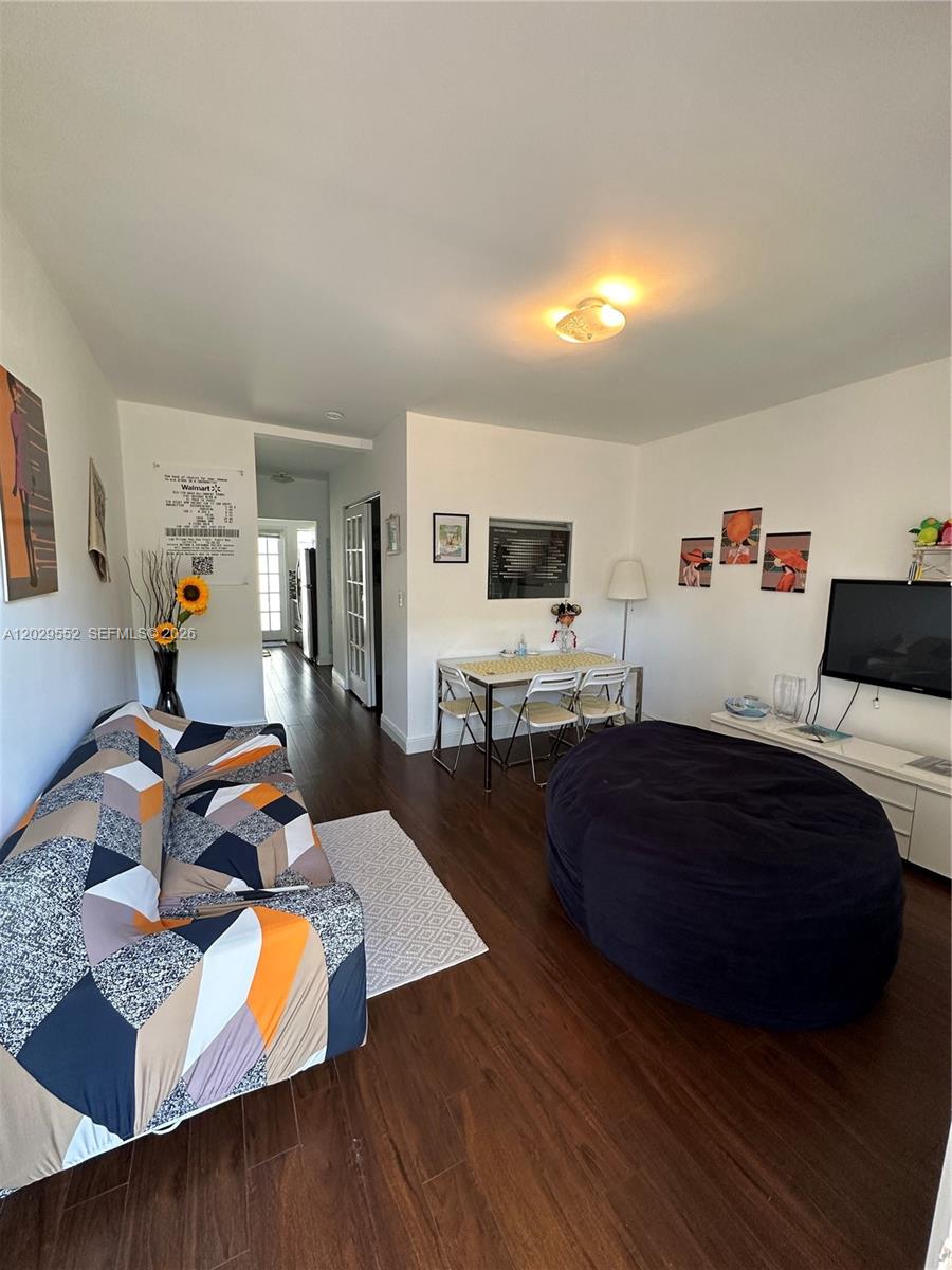 A living room features dark wood flooring, a patterned sofa, and a large beanbag chair — 911 Meridian Ave # 206, Miami Beach FL 33139, MIAMI BEACH, FL