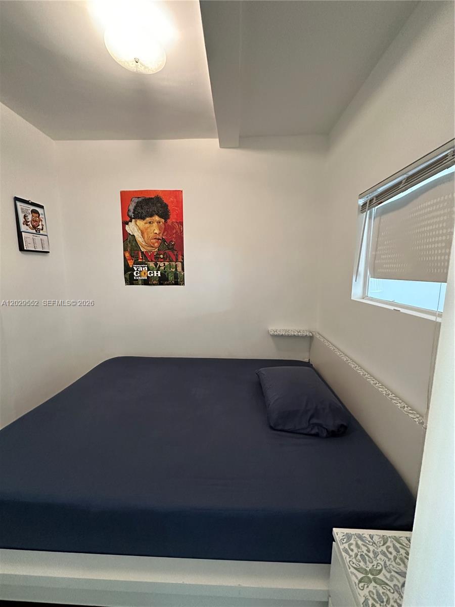 A bedroom features a bed with blue bedding, a window, and wall art — 911 Meridian Ave # 206, Miami Beach FL 33139, MIAMI BEACH, FL