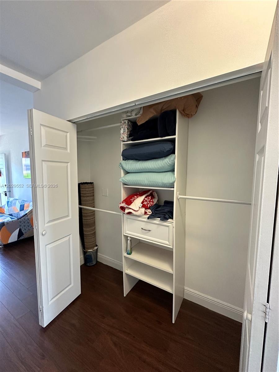 A closet with white shelving, a single drawer, and hanging rods stands in a room — 911 Meridian Ave # 206, Miami Beach FL 33139, MIAMI BEACH, FL