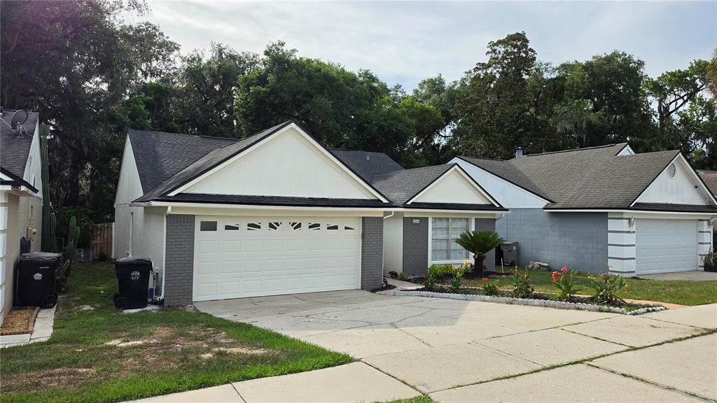 A single-story house with a white garage door, gray brick accents, and a concrete driveway — 204 N CERVIDAE DRIVE, APOPKA, FL