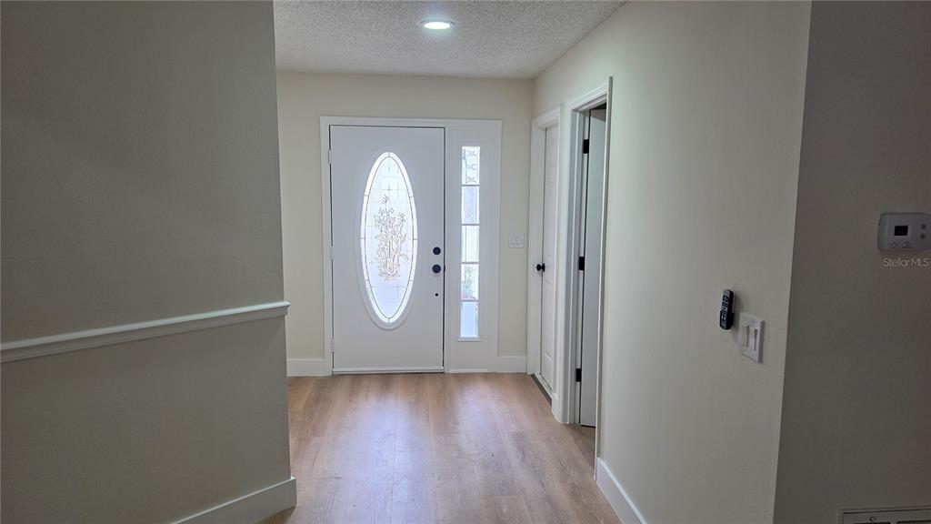 An entryway features light wood-look flooring, a white front door with glass, and neutral walls — 204 N CERVIDAE DRIVE, APOPKA, FL