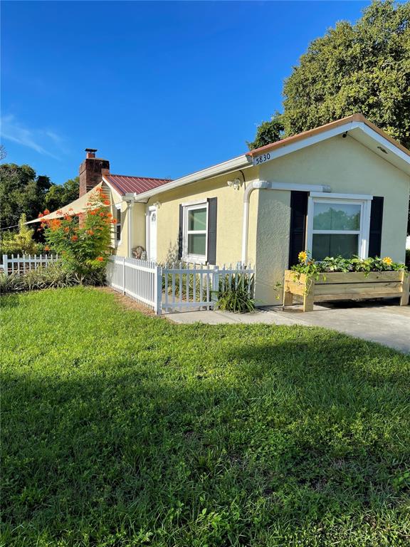 A light yellow house with a red metal roof features a white fence and planter — 5830 ALLIGATOR LAKE SHORE W, ST CLOUD, FL
