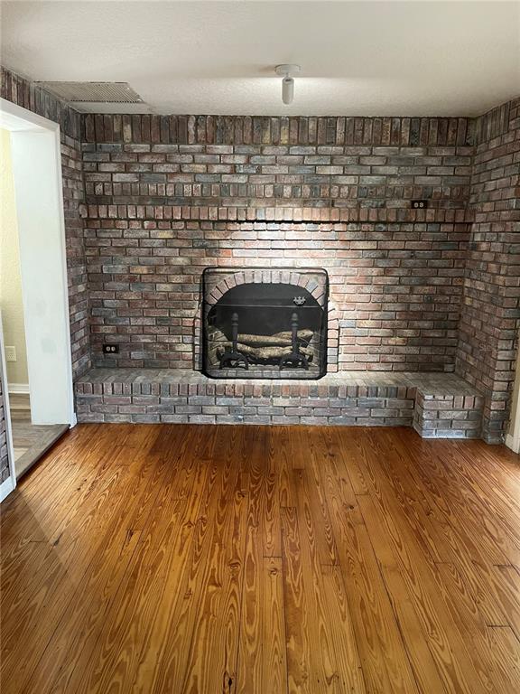 A room with hardwood floors features a large, floor-to-ceiling brick fireplace with a raised hearth — 5830 ALLIGATOR LAKE SHORE W, ST CLOUD, FL