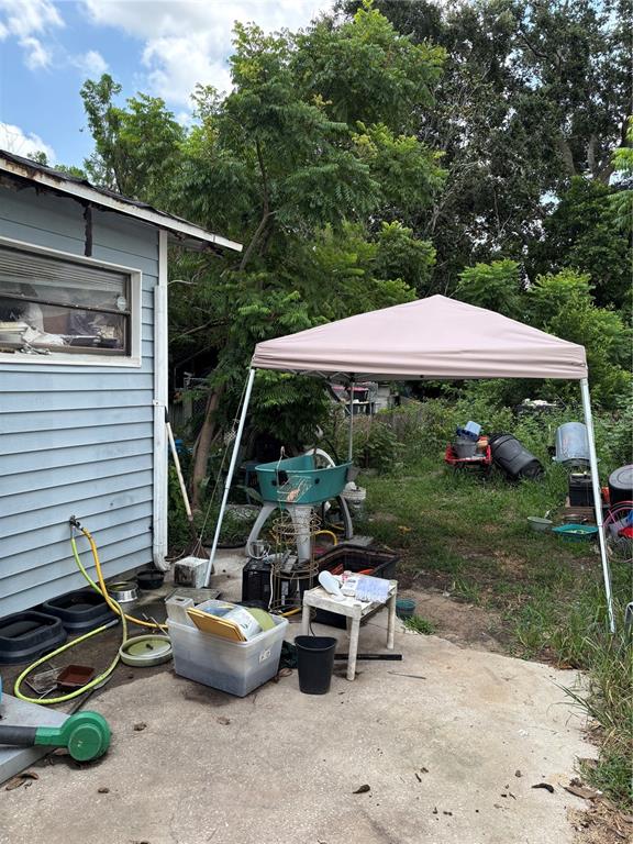 A light blue house exterior features a beige pop-up canopy over a cluttered concrete patio — 110 E TURGOT AVENUE, EDGEWATER, FL