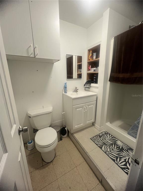 A small bathroom features a white vanity, a toilet, a shower stall, and wall-mounted cabinets — 3887 E US HIGHWAY 90, LAKE CITY, FL