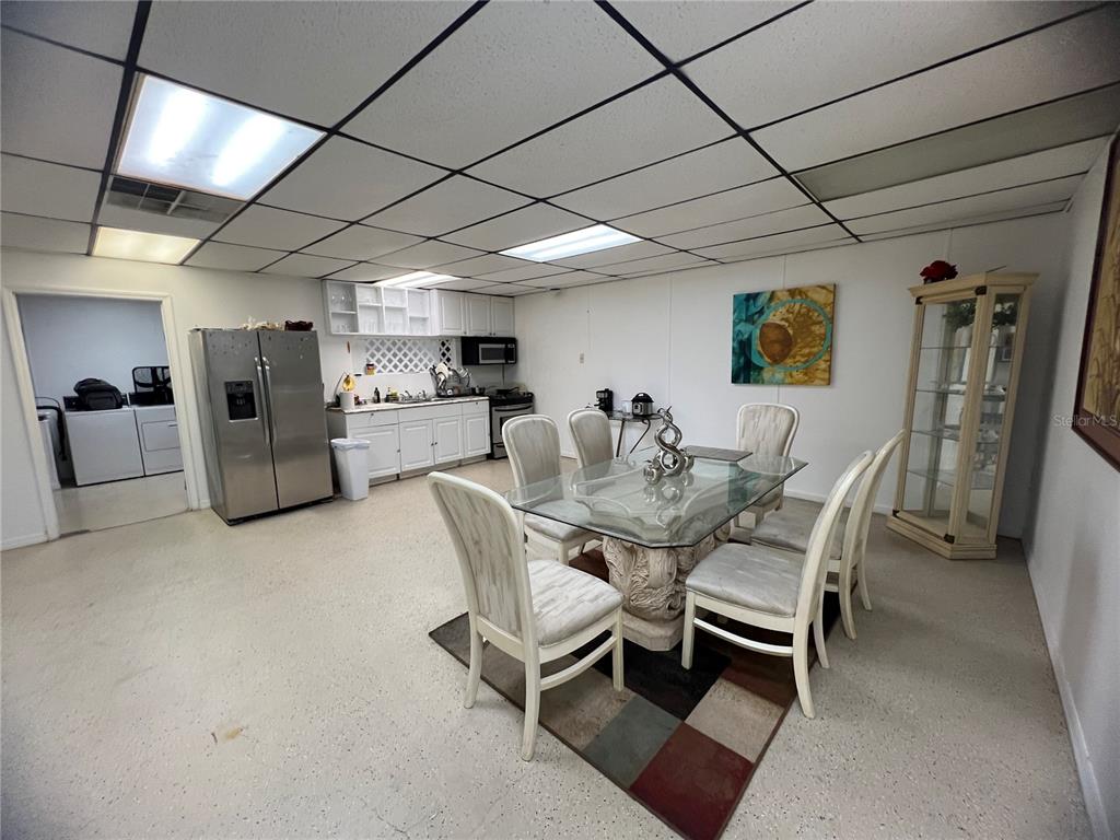 A dining area with a glass table, six chairs, and a small kitchen with appliances — 3887 E US HIGHWAY 90, LAKE CITY, FL