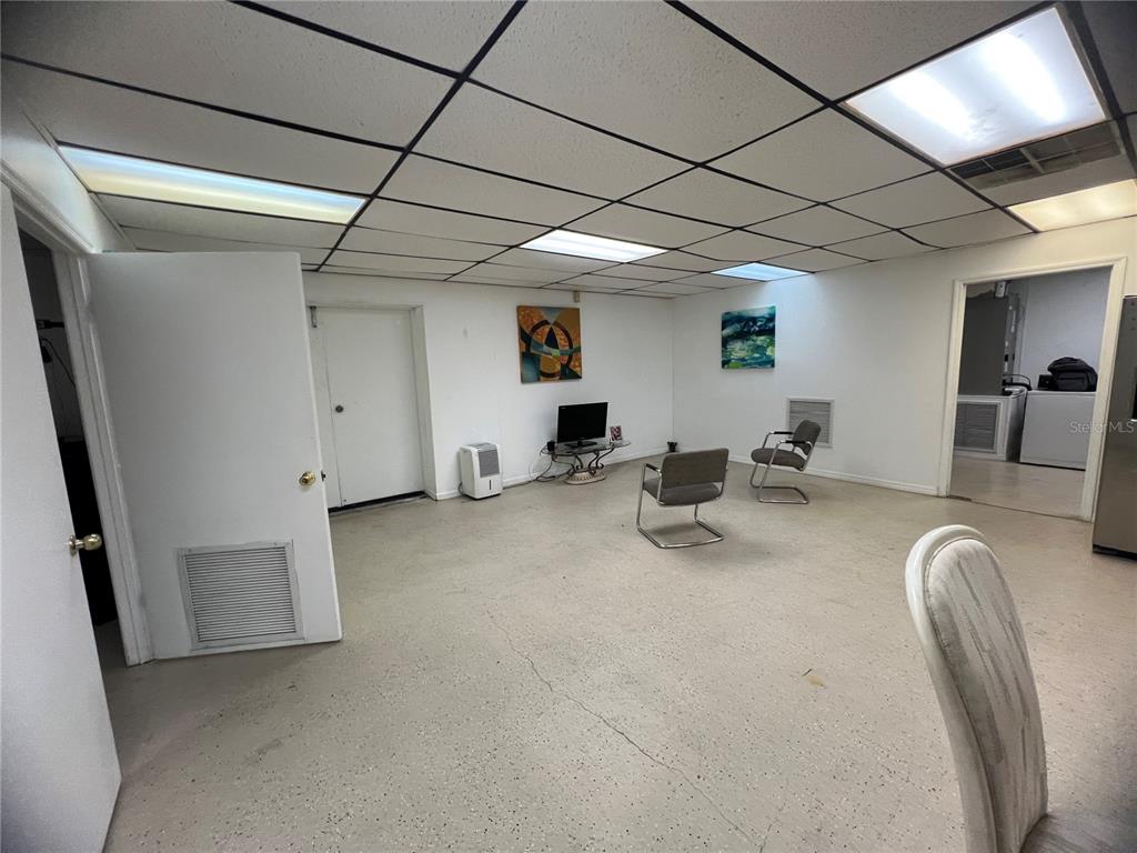 A room with a drop ceiling, concrete floor, two chairs, and a small television — 3887 E US HIGHWAY 90, LAKE CITY, FL
