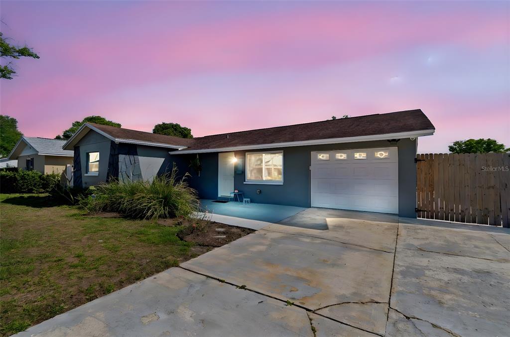 A single-story house with a gray exterior, a white garage door, and a concrete driveway — 6882 62ND AVENUE N, PINELLAS PARK, FL