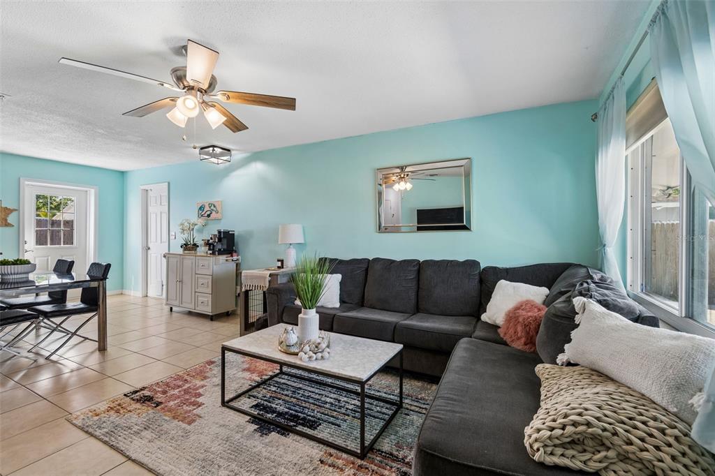 A living room features a gray sectional sofa, a marble coffee table, and light blue walls — 6882 62ND AVENUE N, PINELLAS PARK, FL