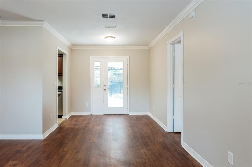 A dining area with wood-look flooring, crown molding, and a glass door leading outside — 9359 TOBY LANE, ORLANDO, FL