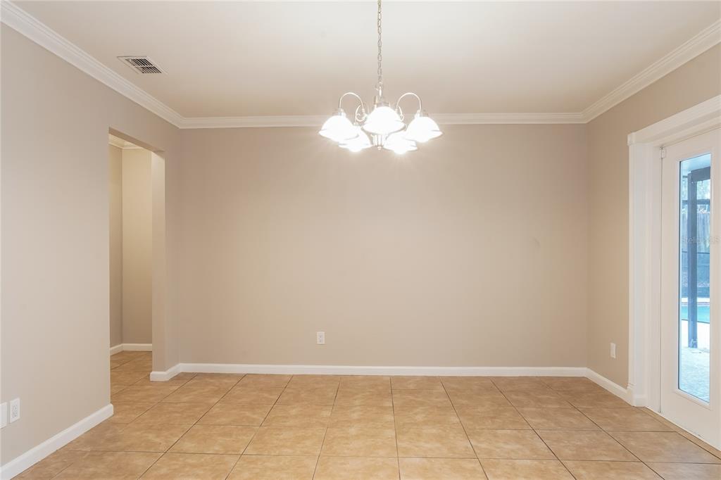 A dining area features beige walls, tile flooring, a chandelier, and a glass-paned door — 9359 TOBY LANE, ORLANDO, FL