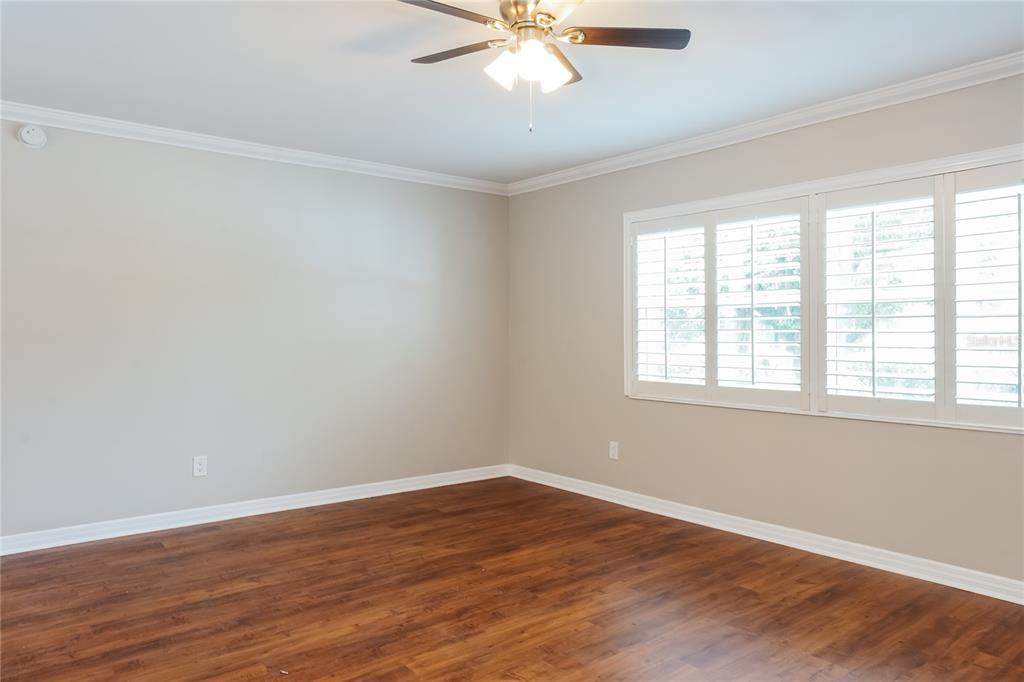 An empty room features wood-look flooring, beige walls, a ceiling fan, and plantation shutters — 9359 TOBY LANE, ORLANDO, FL