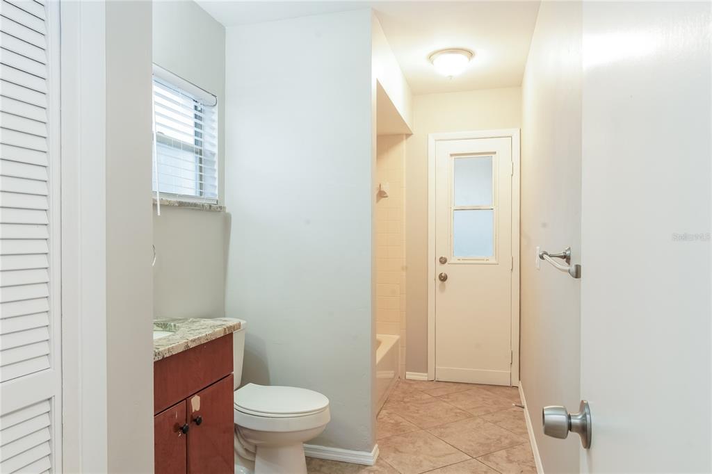 A bathroom features a vanity, toilet, tiled floor, and a door leading outside — 9359 TOBY LANE, ORLANDO, FL