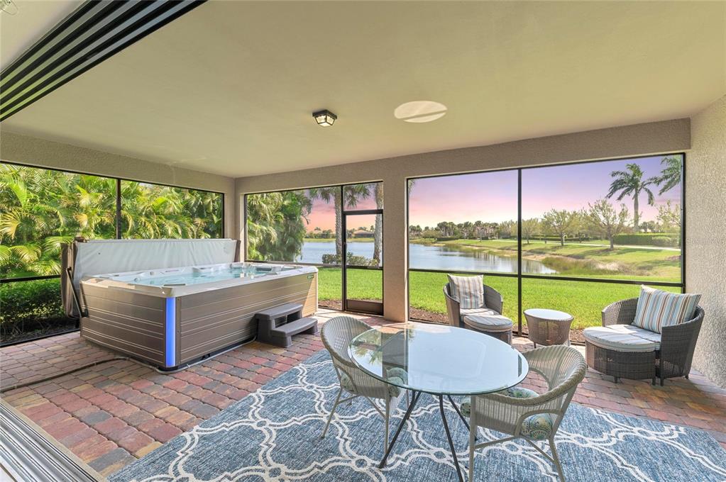 A screened-in patio features a hot tub, outdoor furniture, and a view of a lake — 13785 TOMARO STREET, VENICE, FL