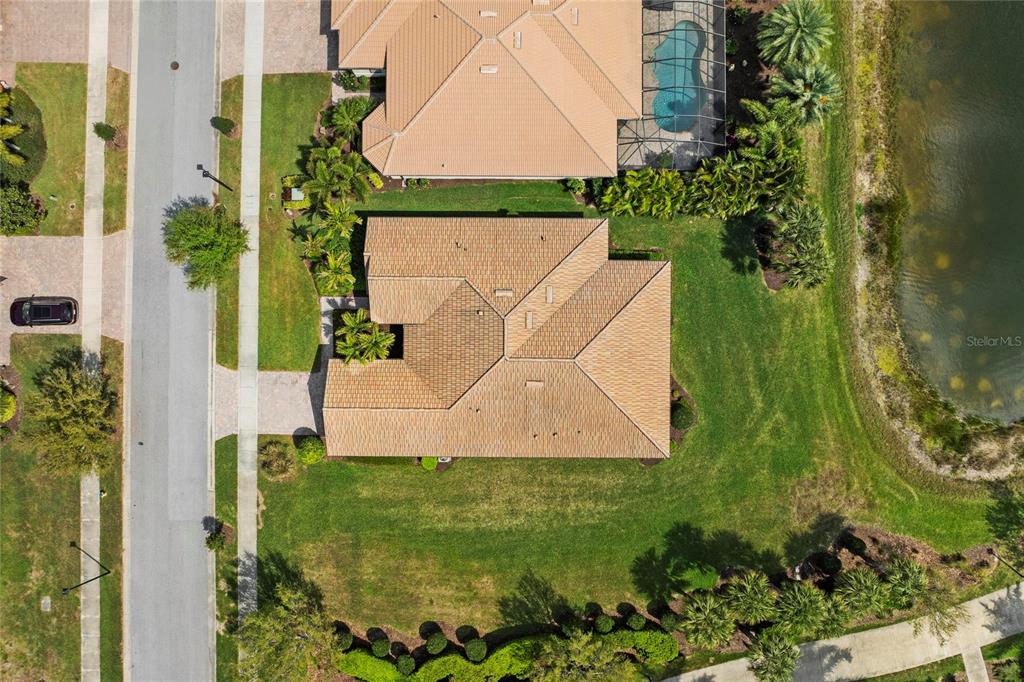 An aerial view shows a house with a tan roof, a driveway, and a large lawn — 13785 TOMARO STREET, VENICE, FL