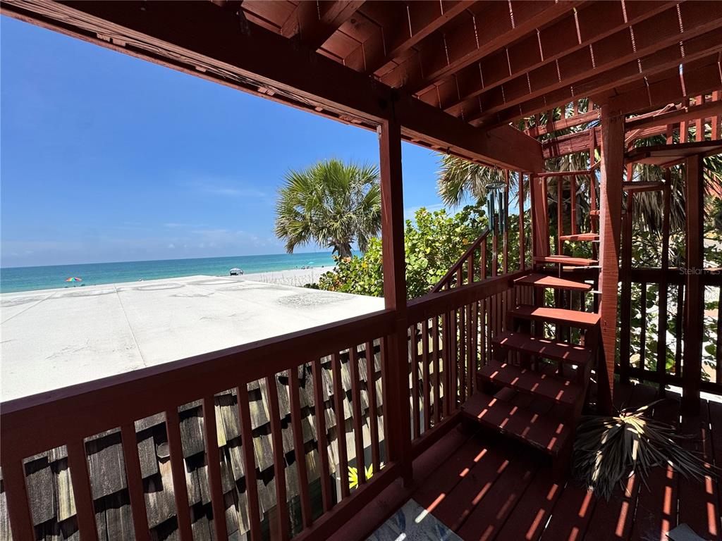 A wooden staircase leads from a covered deck overlooking a beach and the ocean — 18838 GULF BOULEVARD UNIT 202, INDIAN SHORES, FL