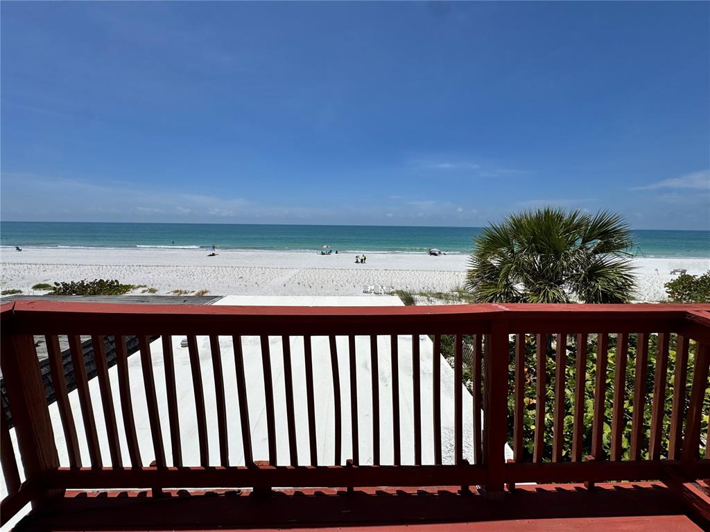A view of a white sand beach and the ocean from a wooden balcony — 18838 GULF BOULEVARD UNIT 202, INDIAN SHORES, FL