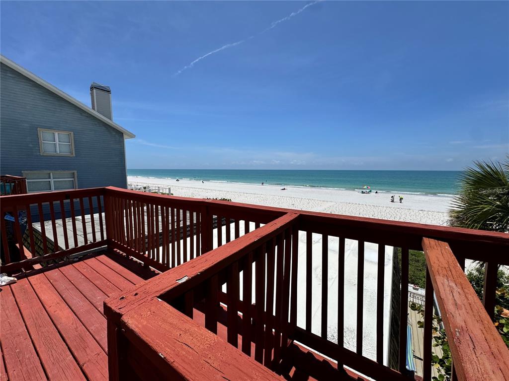 A wooden deck overlooks a sandy beach and the ocean on a sunny day — 18838 GULF BOULEVARD UNIT 202, INDIAN SHORES, FL