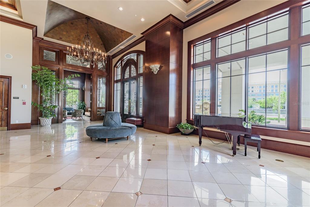 A grand lobby features a vaulted ceiling, chandelier, tile flooring, a piano, and large windows — 345 BAYSHORE BOULEVARD UNIT 1710, TAMPA, FL