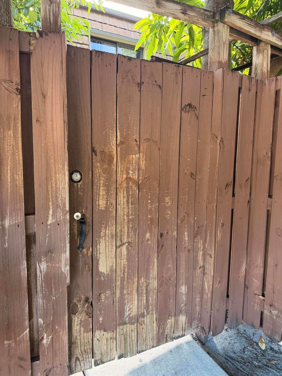 A weathered wooden gate with a black handle and lock stands in a fenced yard — 1421 14th Lane # D, FL 33463, FL