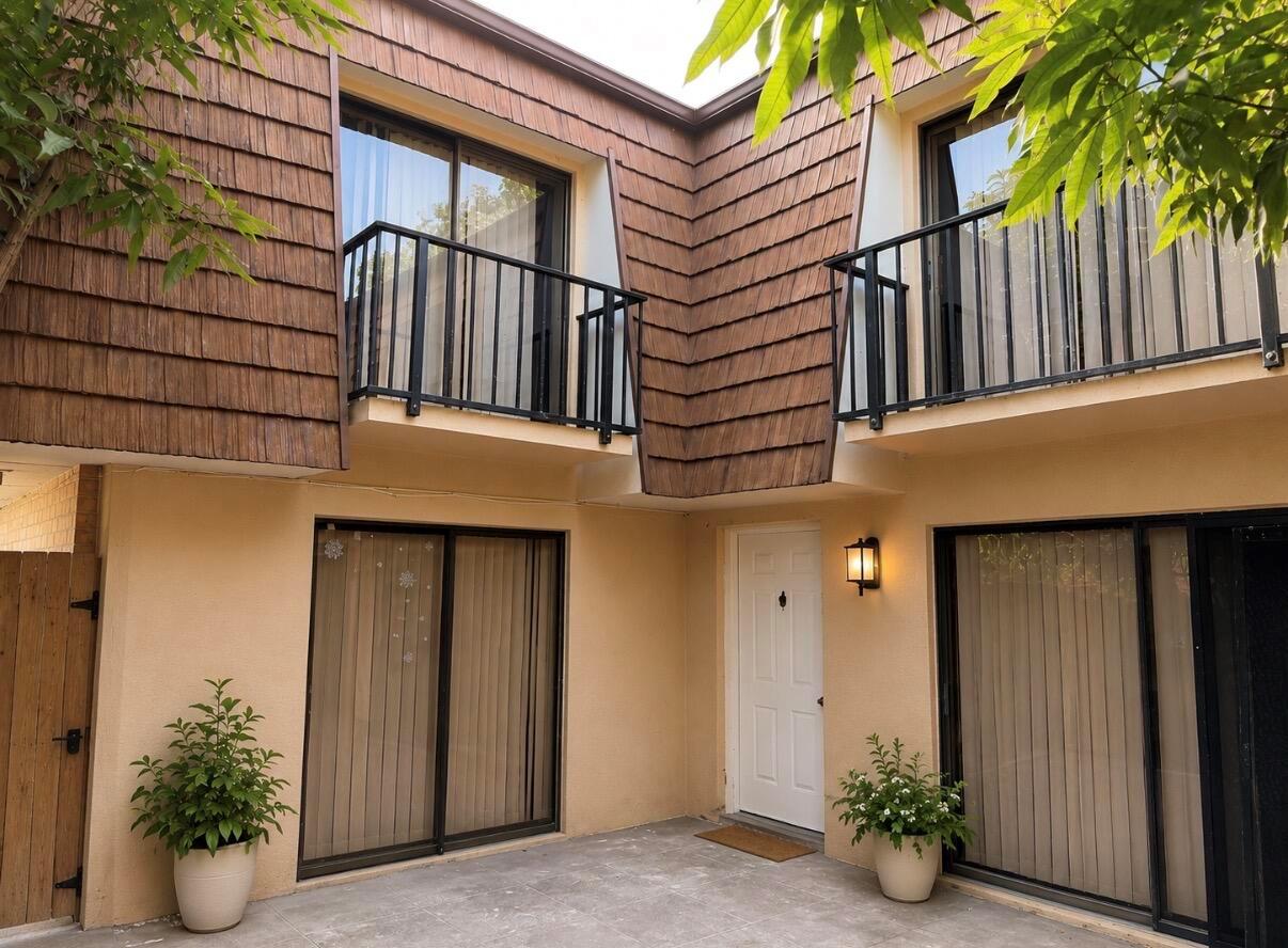 A two-story building exterior with a tiled facade, balconies, sliding glass doors, and a patio — 1421 14th Lane # D, FL 33463, FL