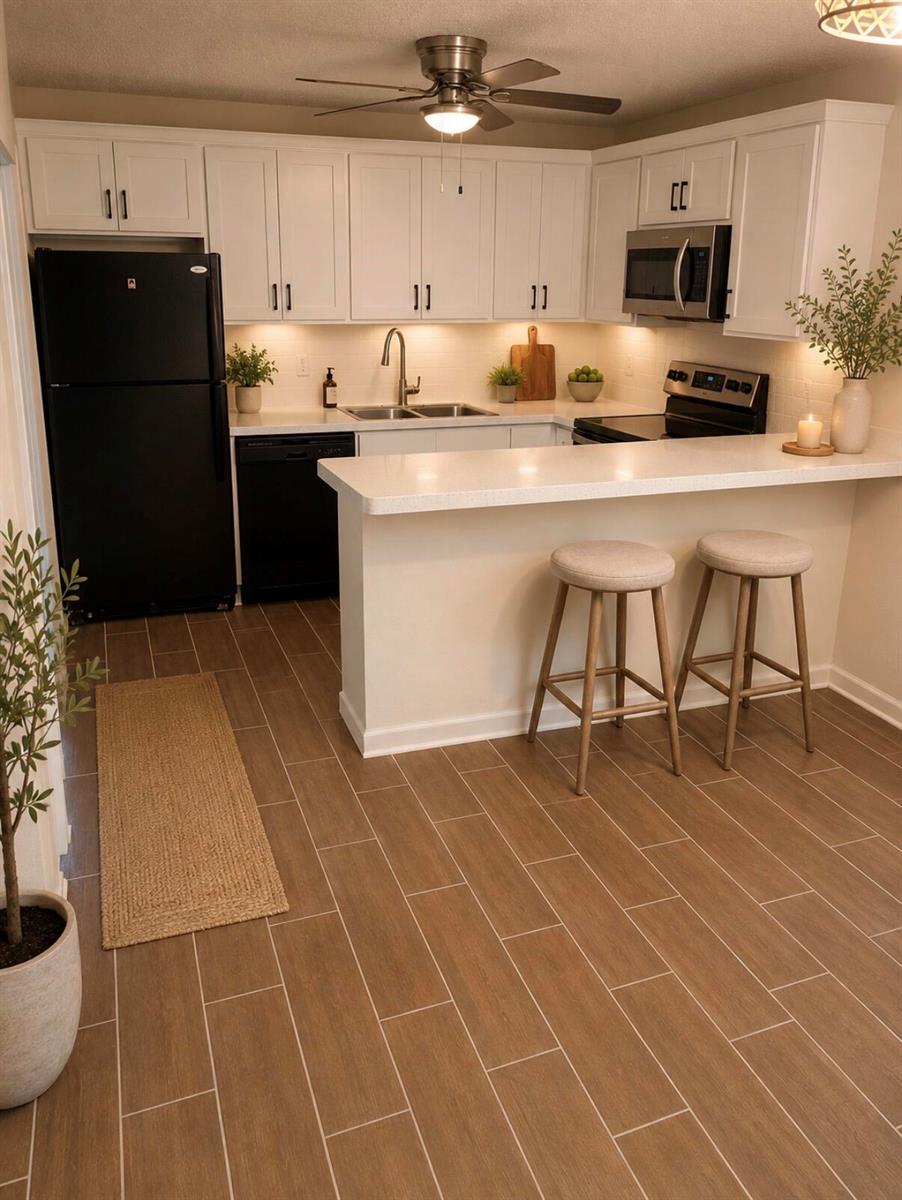 A kitchen with white cabinets, black appliances, a breakfast bar, and wood-look tile flooring — 1421 14th Lane # D, FL 33463, FL