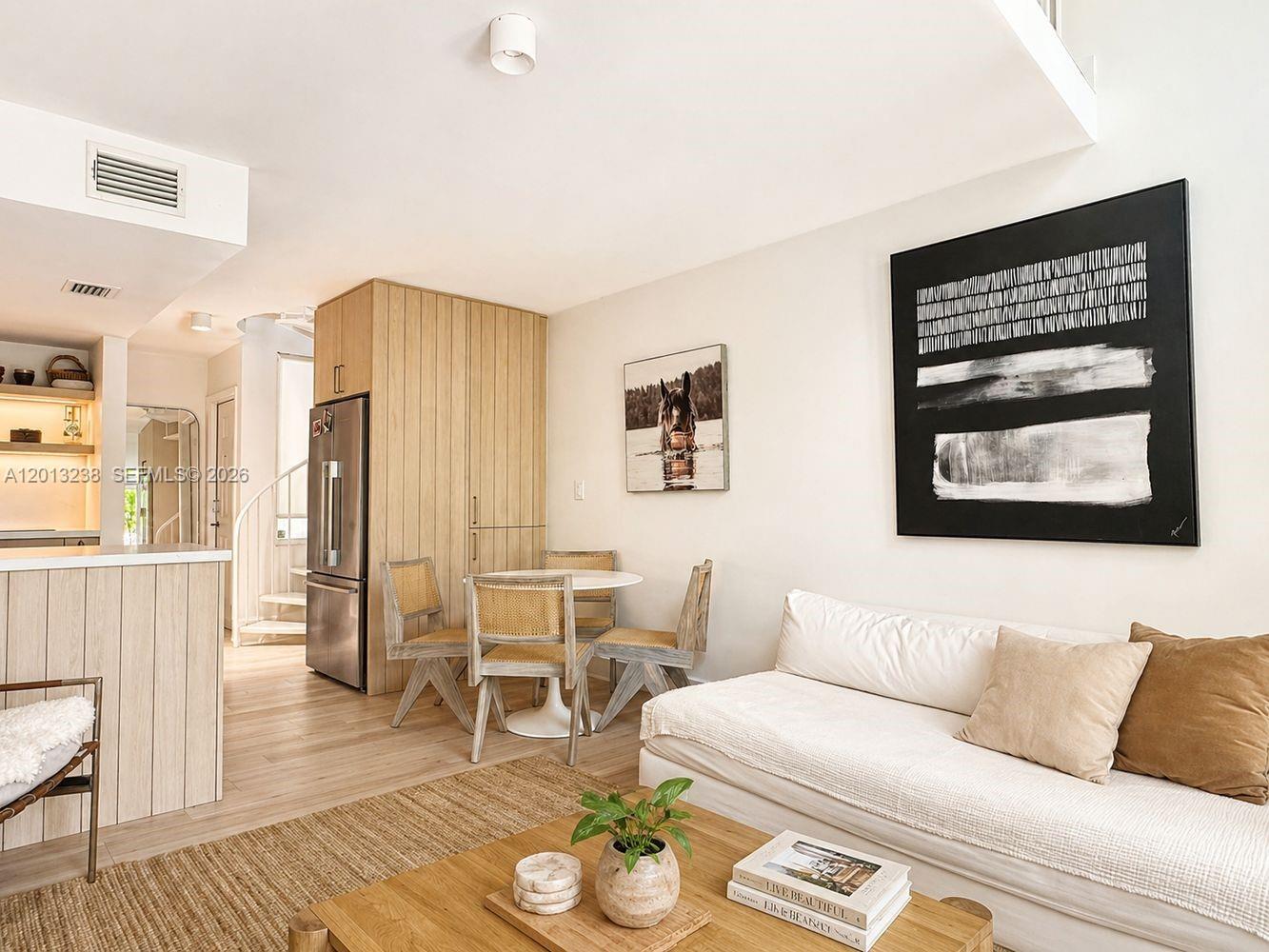 A living and dining area features light wood cabinetry, a white sofa, and a spiral staircase — 2984 Mary St, Miami FL 33133, MIAMI, FL