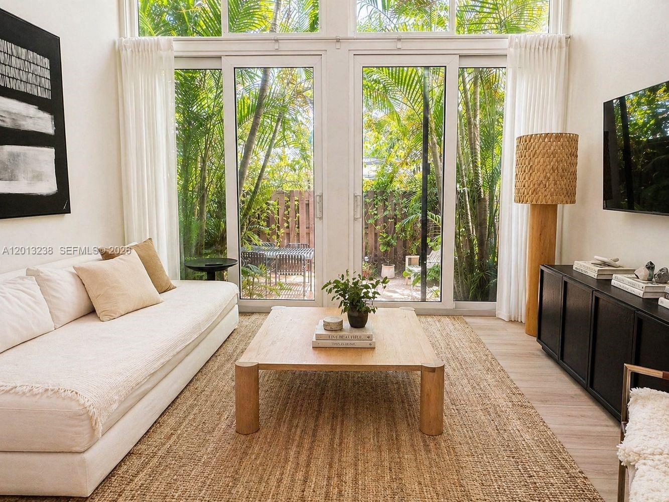 A living room with a white sofa, wooden coffee table, and floor-to-ceiling glass doors — 2984 Mary St, Miami FL 33133, MIAMI, FL