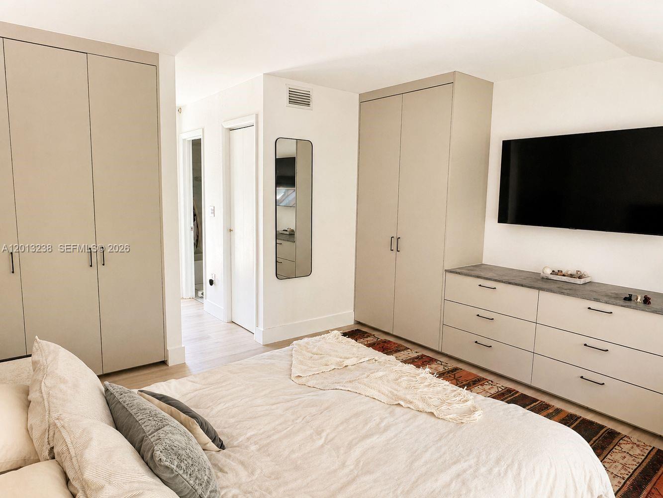A bedroom features light-colored cabinetry, a dresser, a wall-mounted television, and a bed — 2984 Mary St, Miami FL 33133, MIAMI, FL