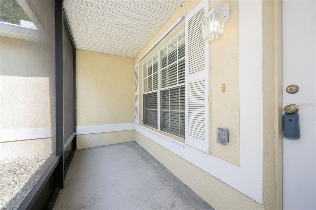 A covered patio features a concrete floor, a screened wall, and a window with shutters — 1491 16TH STREET, ORANGE CITY, FL