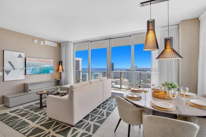 A modern living and dining room with a sectional sofa, ocean views, and pendant lighting — 4010 S Ocean Dr # R2708, Hollywood FL 33019, HOLLYWOOD, FL