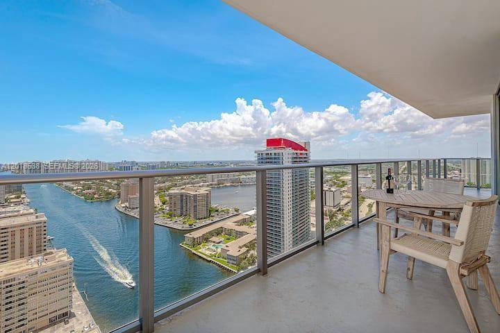 A high-rise balcony with a table and chairs overlooking a waterway and city skyline — 4010 S Ocean Dr # R2708, Hollywood FL 33019, HOLLYWOOD, FL