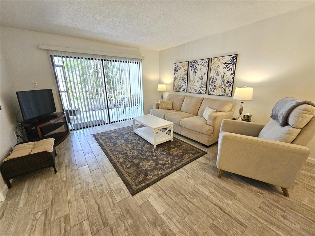 A living room features light tile flooring, a beige sofa, an armchair, and sliding glass doors — 5286 WILLOW LINKS UNIT 59, SARASOTA, FL
