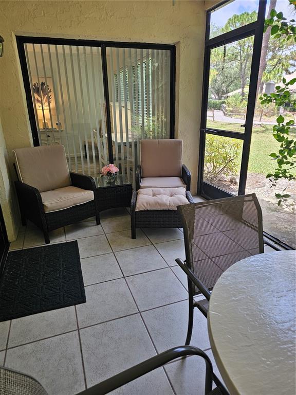 A screened-in patio features tiled flooring, wicker furniture, and a view of the outdoors — 5286 WILLOW LINKS UNIT 59, SARASOTA, FL